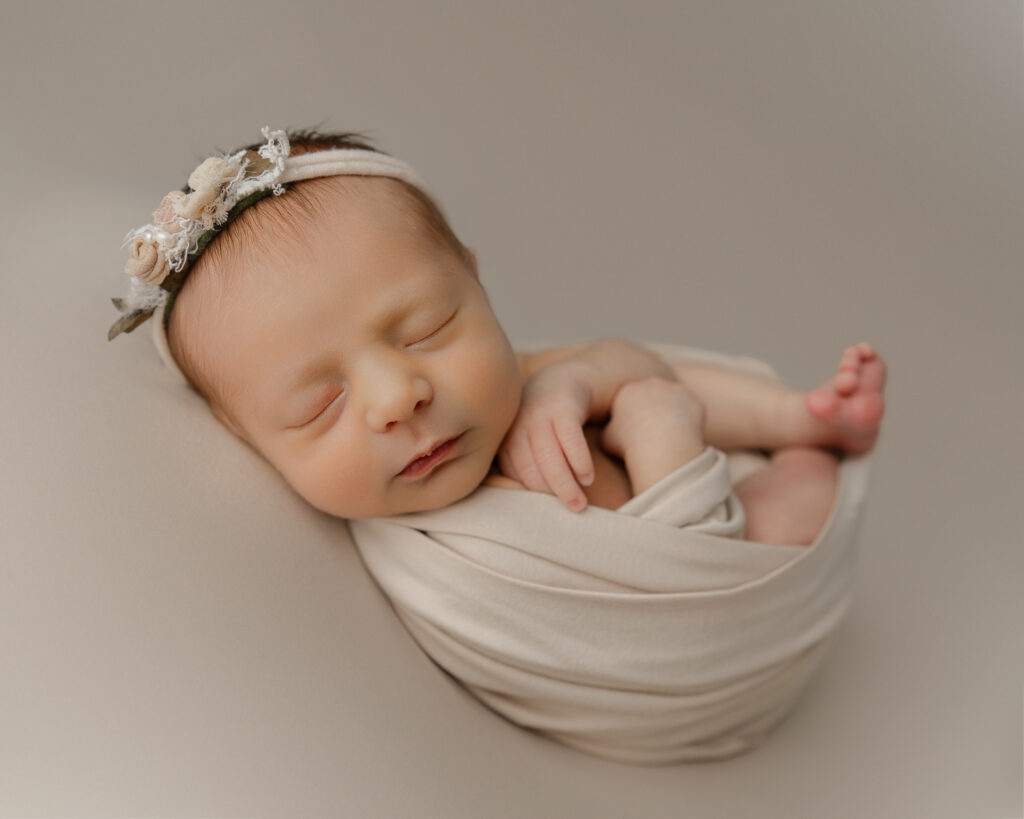 Timeless newborn photo outfit ideas with a neutral wrap and soft floral headband for classic newborn photography
