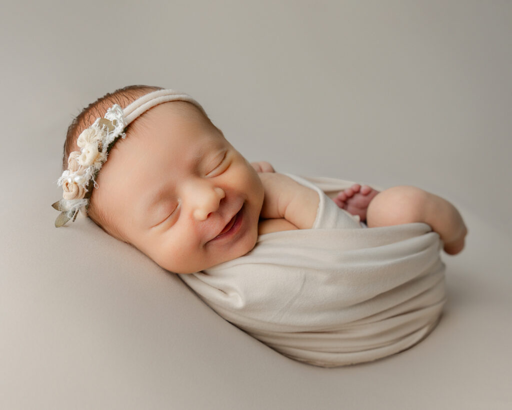Newborn photo outfit ideas featuring a baby wrapped in soft neutral tones for a timeless look