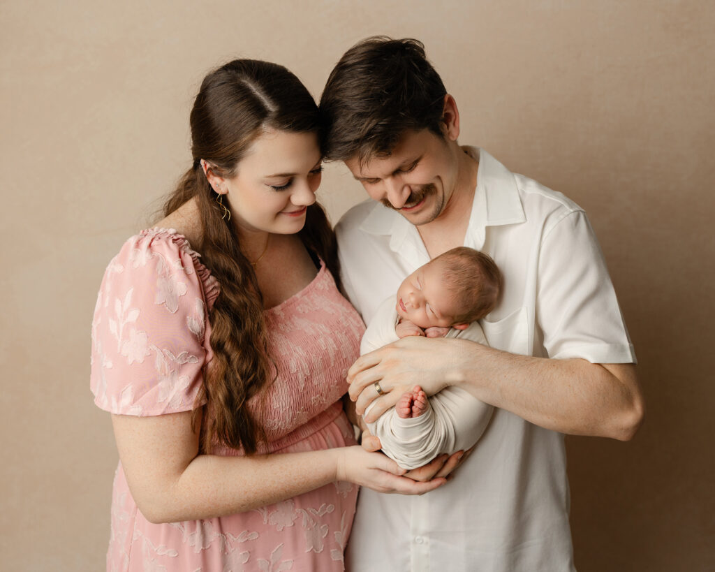 New parents looking down at their newborn baby during a Beaumont family photography studio session, highlighting connection and tenderness.