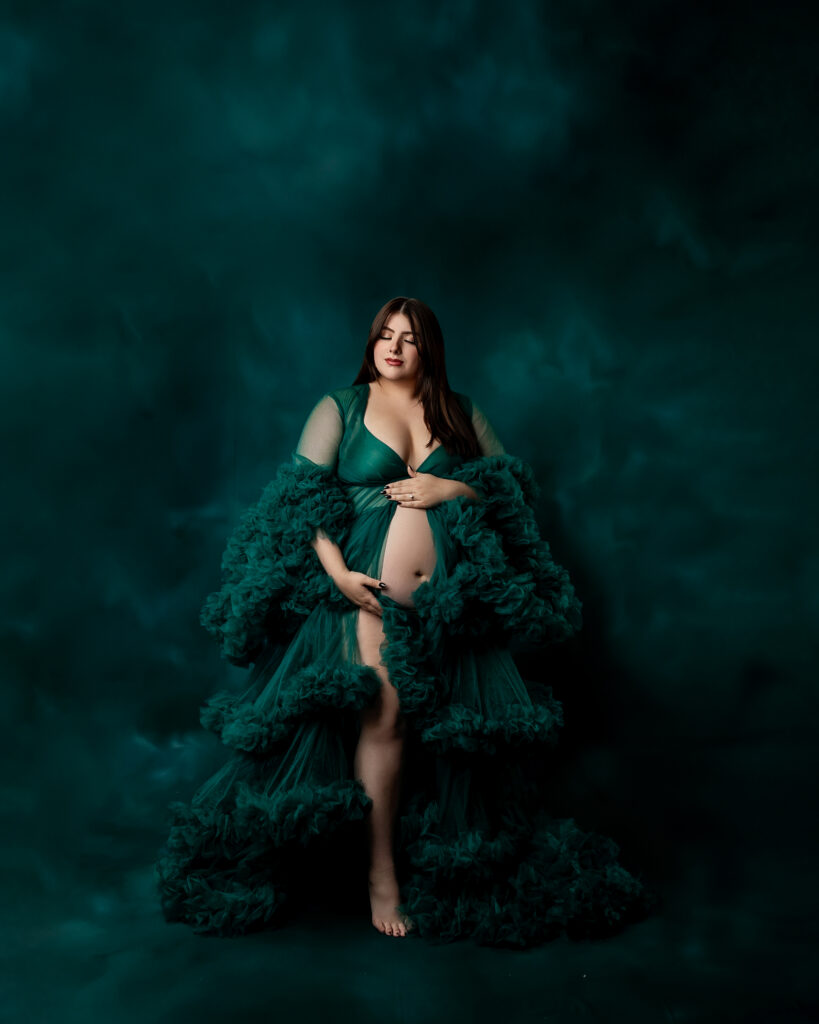 A breathtaking moment of motherhood captured in emerald tones—this mama-to-be radiates strength and grace as she holds her growing belly. Photograph by Inland Empire motherhood photographer Kaitlyn Dawn Photography.