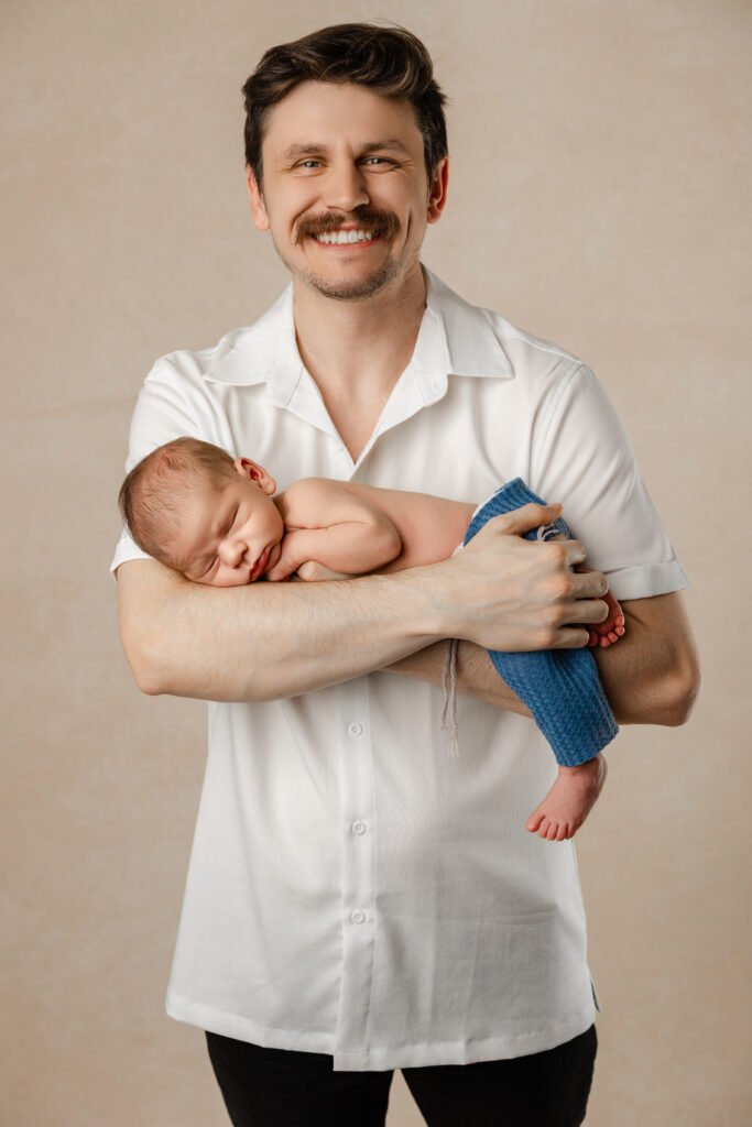 Father holding newborn during a newborn photography session in the Inland Empire by Kaitlyn Dawn Photography