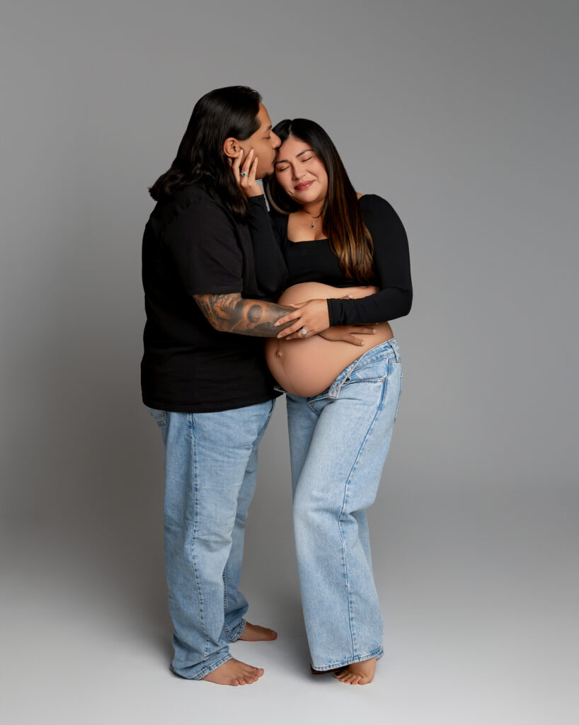 Inland Empire maternity photography session with expectant mother and partner wearing black tops and denim, highlighting connection and pregnancy