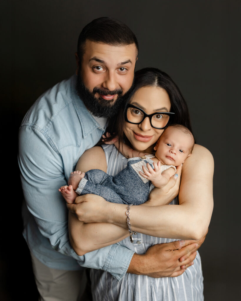 Parents cuddling their newborn during a family portrait session, highlighting comfort and bonding.
