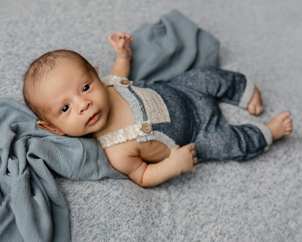 Baby in a knit romper resting comfortably on a textured blanket, representing safe sleep education and topics related to a sleeping position for colic baby. Photograph by Yucaipa newborn photographer Kaitlyn Dawn Photography.