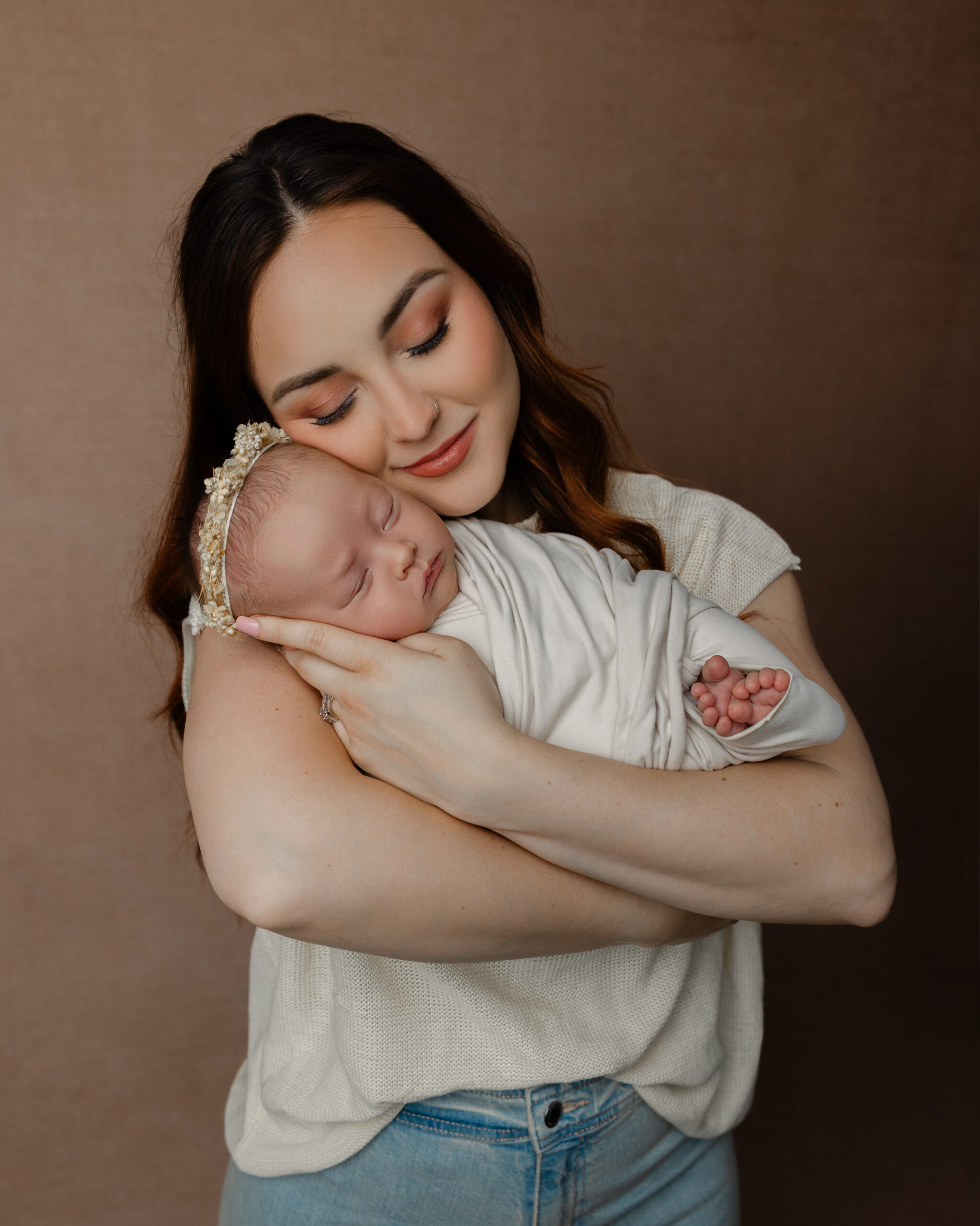 Mother holding her sleeping newborn wrapped in white fabric during a studio session that reflects how motherhood changes you. Photograph by Kaitlyn Dawn Photography.