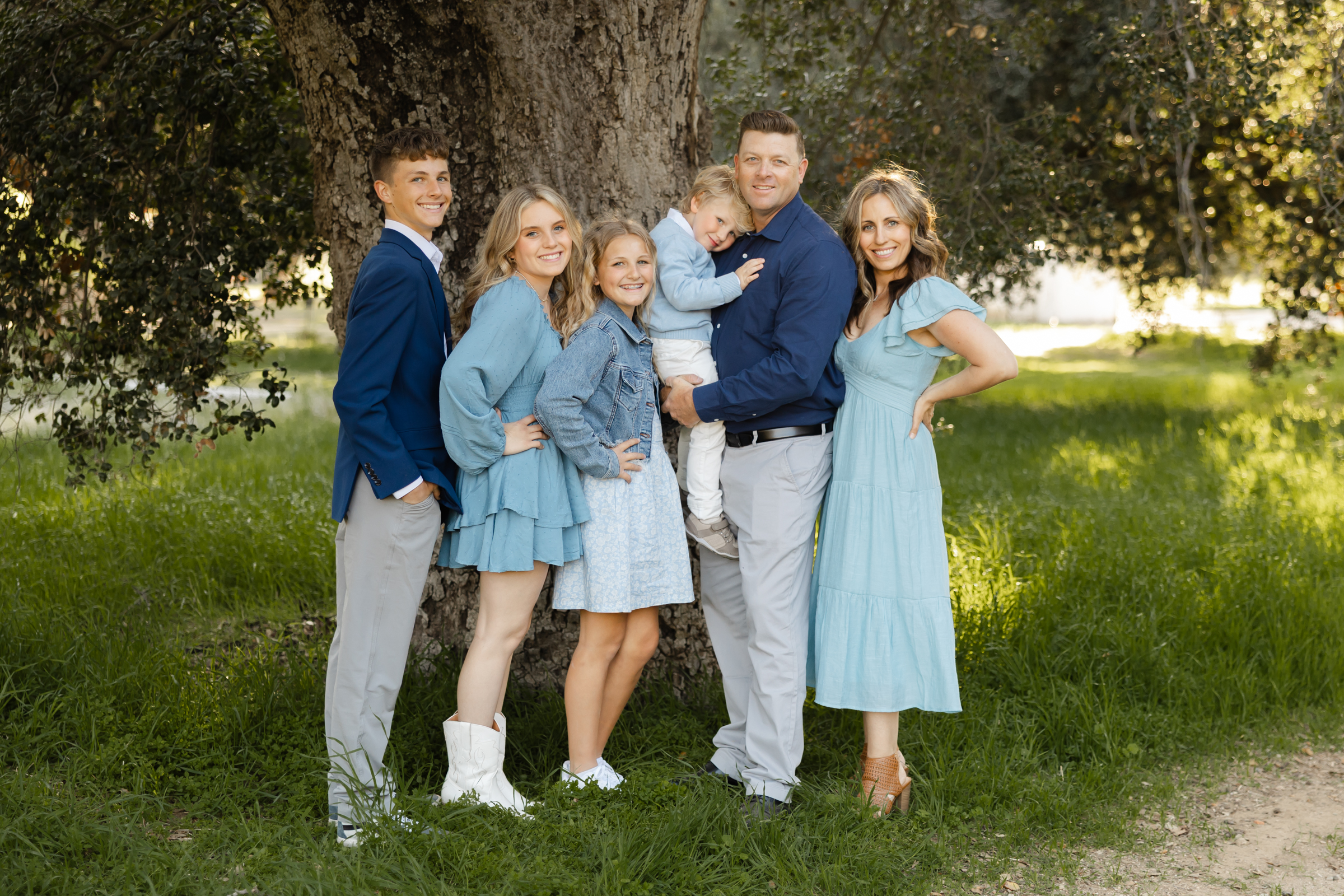 Family standing together under a large oak tree in a peaceful outdoor setting, showcasing relaxed things to do in Yucaipa, photographed by Kaitlyn Dawn Photography.