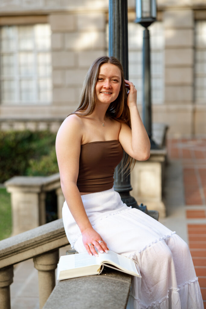 Senior sitting with a book during her portrait session, showing how personal details can create natural senior photos captured by Kaitlyn Dawn Photography