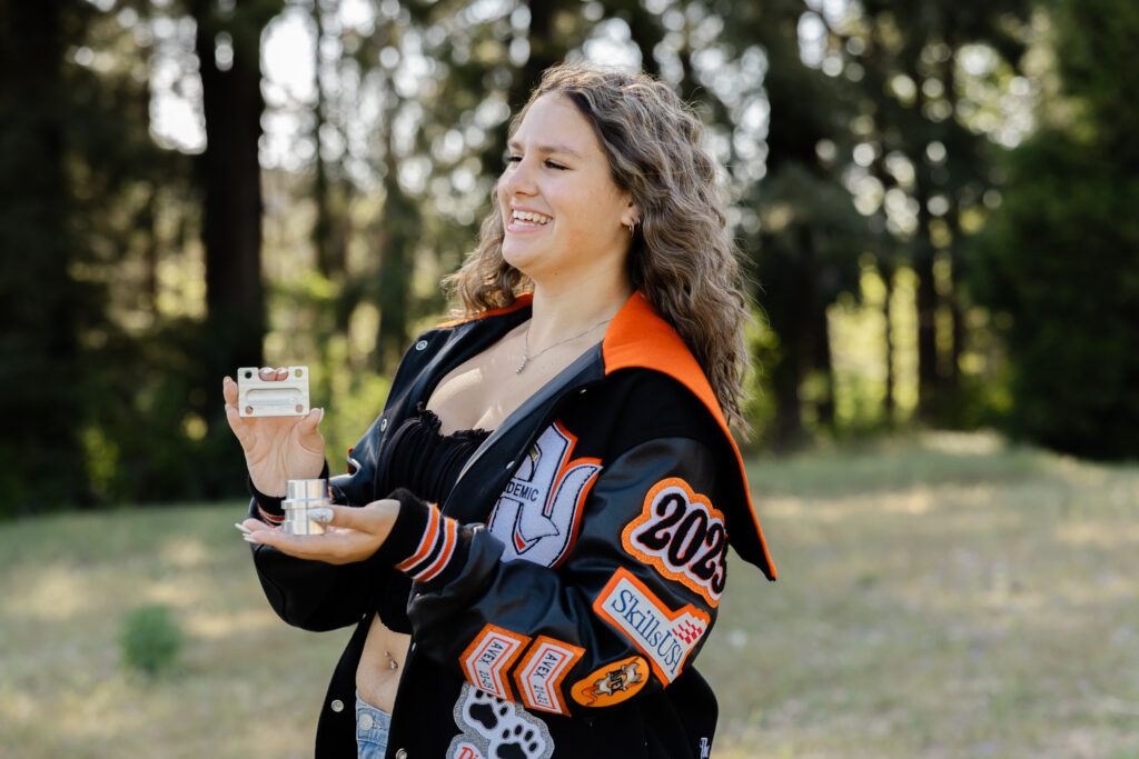High school senior in a letterman jacket holding a personal item, capturing natural poses for senior photos with meaningful props.