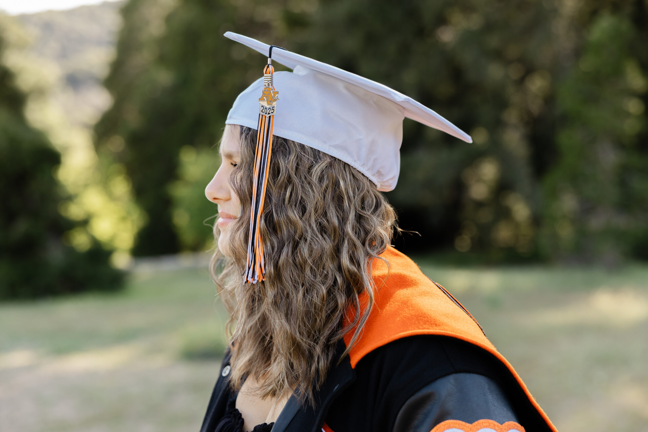 Senior pictures of a Yucaipa High School graduate wearing her cap, tassel, and letterman jacket outdoors.