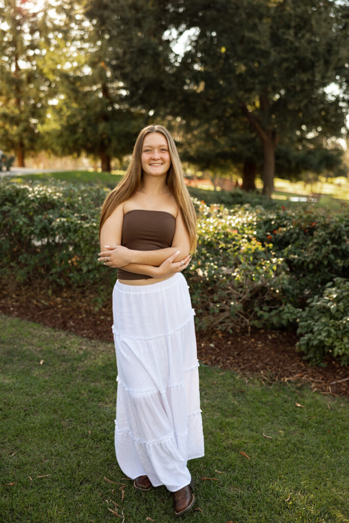 Senior standing confidently in a garden during a warm, natural senior photography session.
