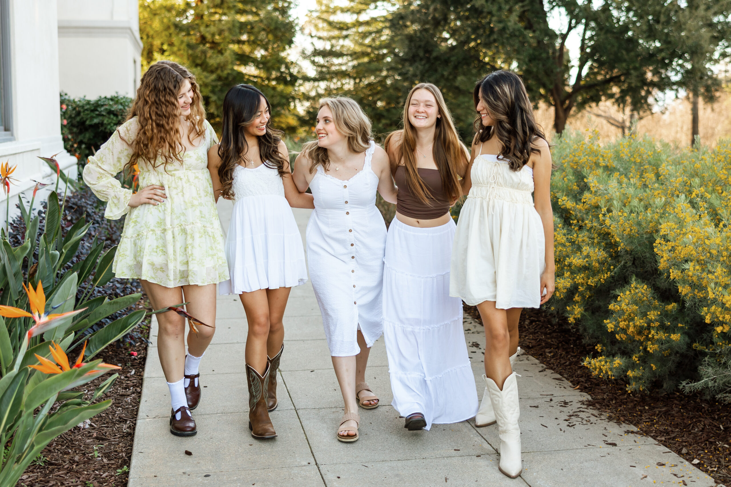 High school seniors walking together and laughing outdoors, capturing fun and candid senior friend photos during their session in Yucaipa by Kaitlyn Dawn Photography.