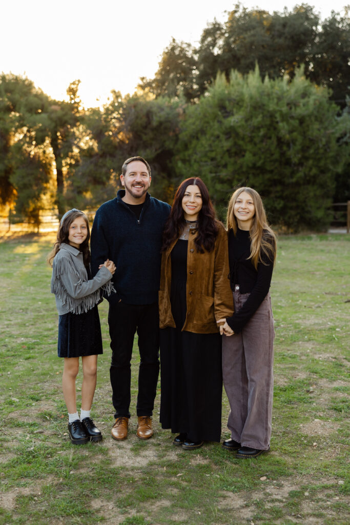 Classic portrait showing photography styles for families with parents and daughters smiling together during a relaxed golden hour session in nature by Kaitlyn Dawn Photography.