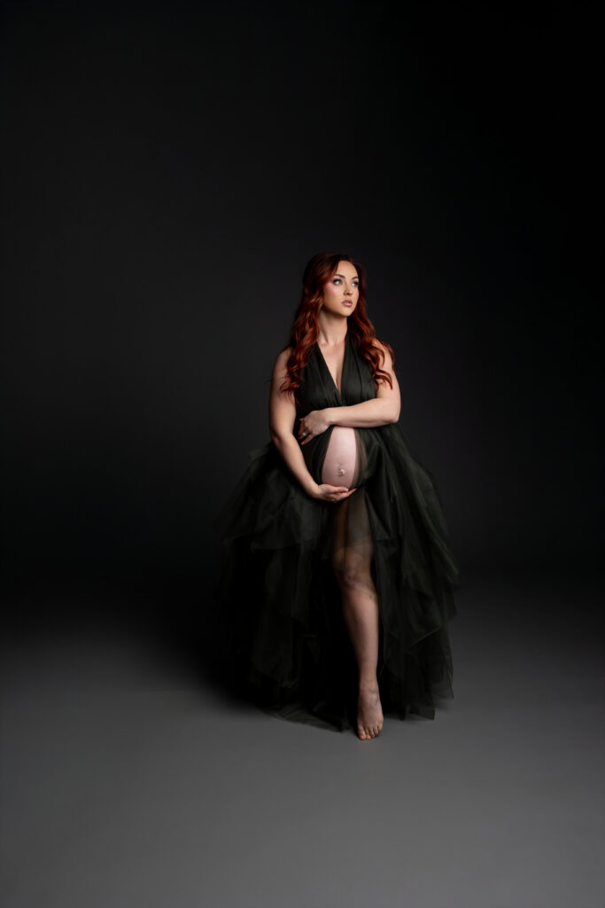 Fine art maternity portrait with dark backdrop and dramatic styling representing the emotional beauty of the hardest week of pregnancy. Photograph by Redlands maternity photographer Kaitlyn Dawn Photography.