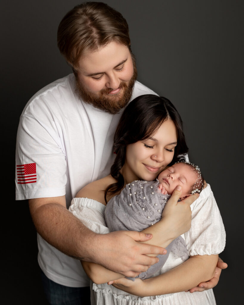 Parents comforting their newborn during newborn photography session in Yucaipa.
