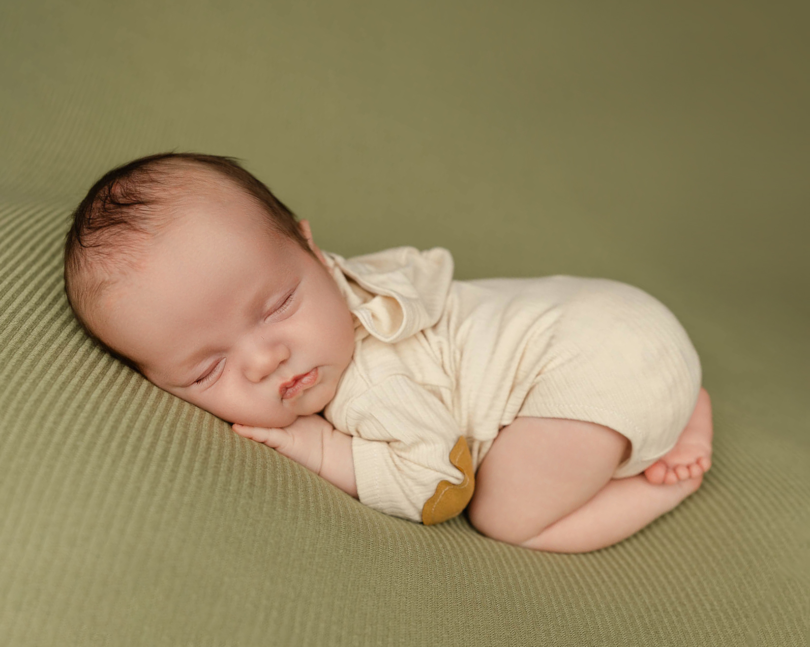 Curled-up infant resting comfortably during a 6 week newborn milestone photography session by Kaitlyn Dawn Photography, documenting baby's growth beyond the newborn stage.
