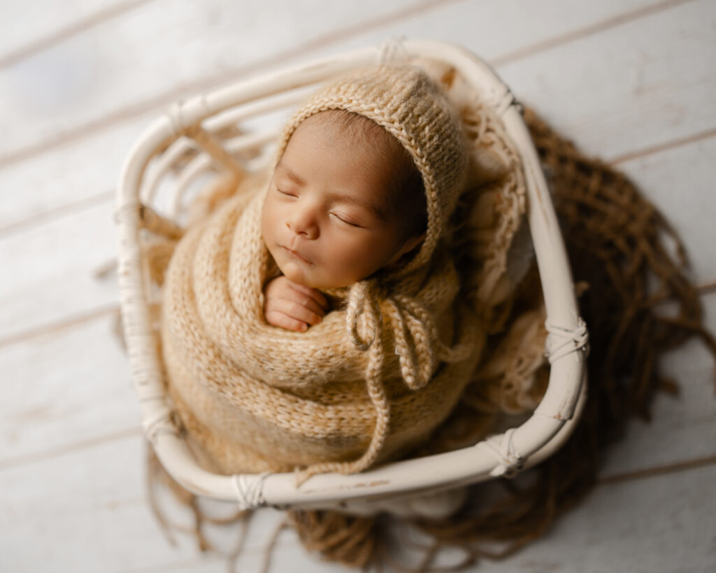 Sleeping baby wrapped in a cream knit outfit and bonnet during a newborn week 3 photography session, showcasing the peaceful moments parents treasure in the early newborn stage.