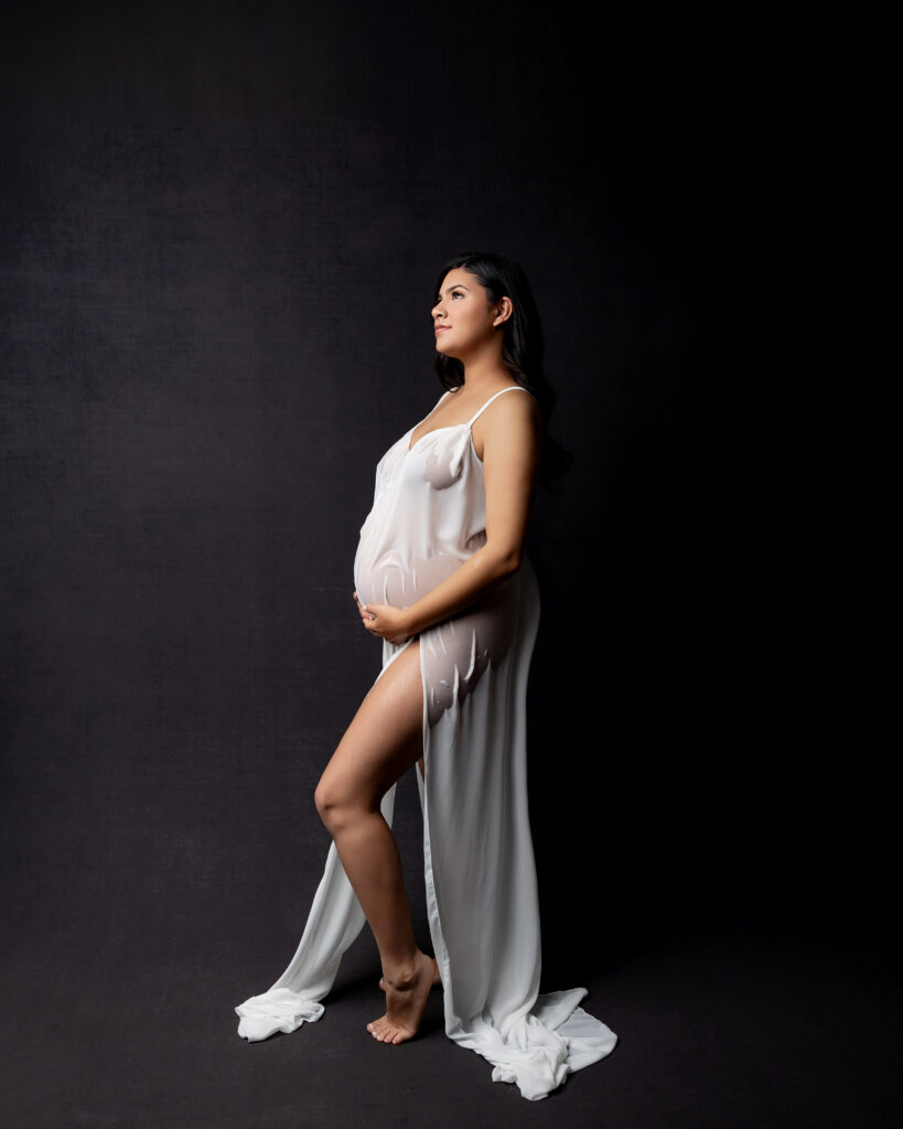 Side-profile maternity portrait highlighting a full-term baby bump and the physical changes that often accompany signs labor is near. Captured by Kaitlyn Dawn Photography.