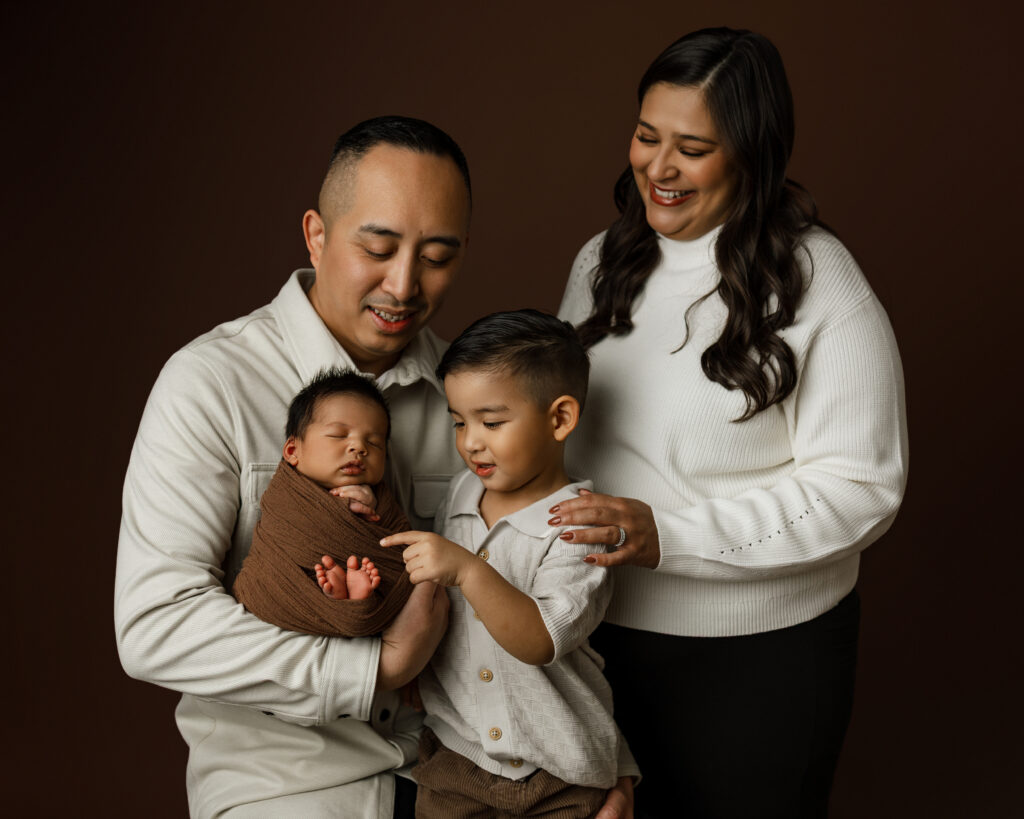 Parents and a sibling with their 6 week old baby during a newborn session in Yucaipa newborn studio, capturing their first family portraits together.