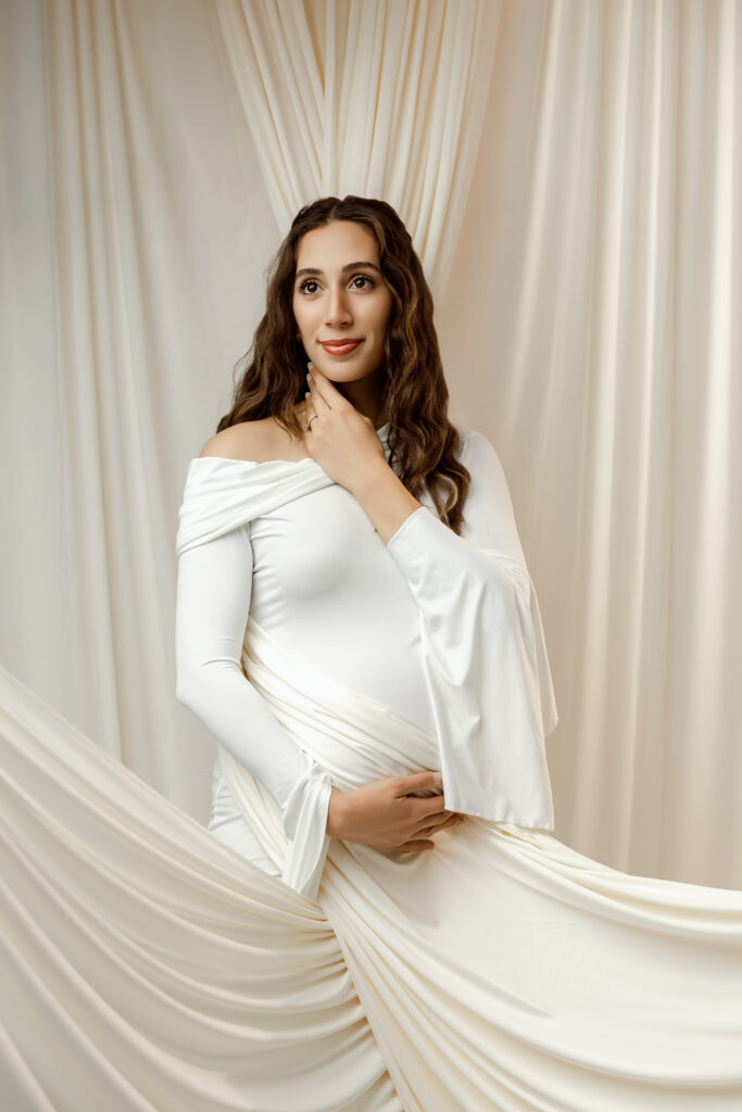 Elegant studio portrait of an expectant mother in a flowing white gown captured by a Yucaipa maternity photographer.